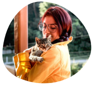 Woman in yellow jacket with grey cat in her arms is the cat parent expressing gratitude to Pawland for their pet sitting
