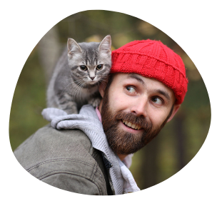 Cat Parent in grey jacket with red cap & grey cat on the shoulder is happy with Pawland’s cat sitters for personalised care
