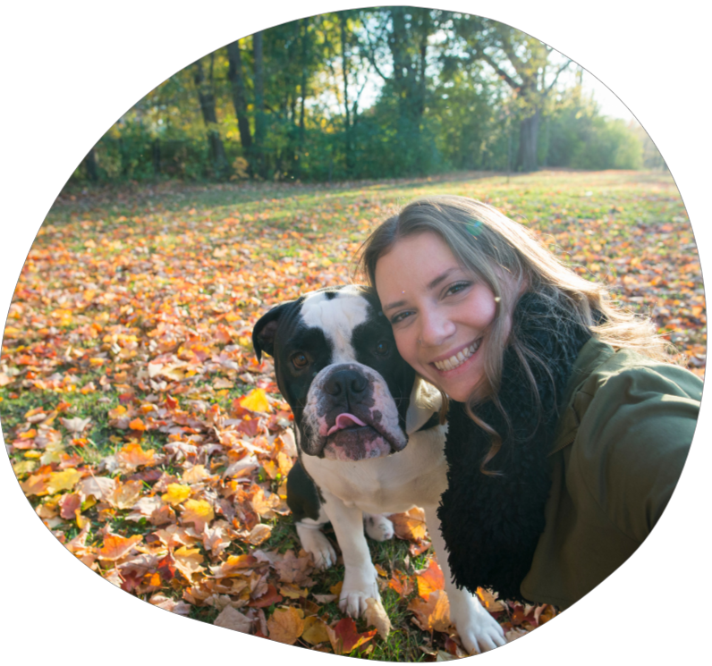 A selfie of a dog walker and dog at a park that is filled with leaves during the fall season