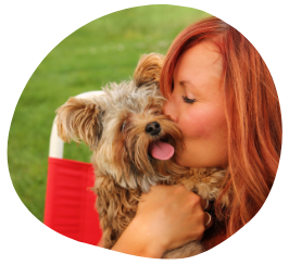 A loving redhead dog sitter hugging a fluffy dog with its tongue out