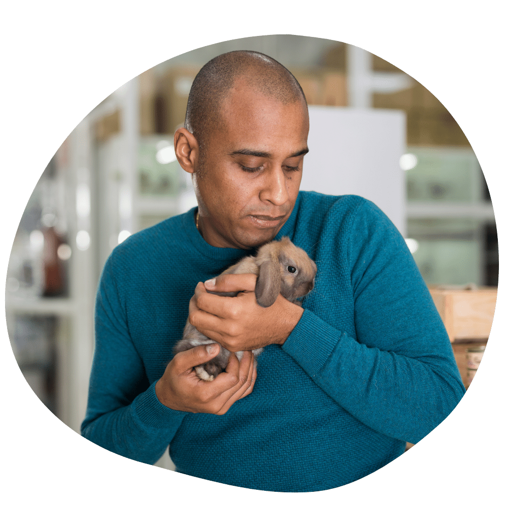 Man wearing blue t-shirt holding small pet rabbit in his hands after Pawland’s pet boarding services in Abu Dhabi