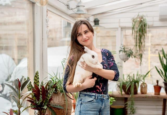 Rabbit owner holding white rabbit in hand after availing in-home pet boarding services