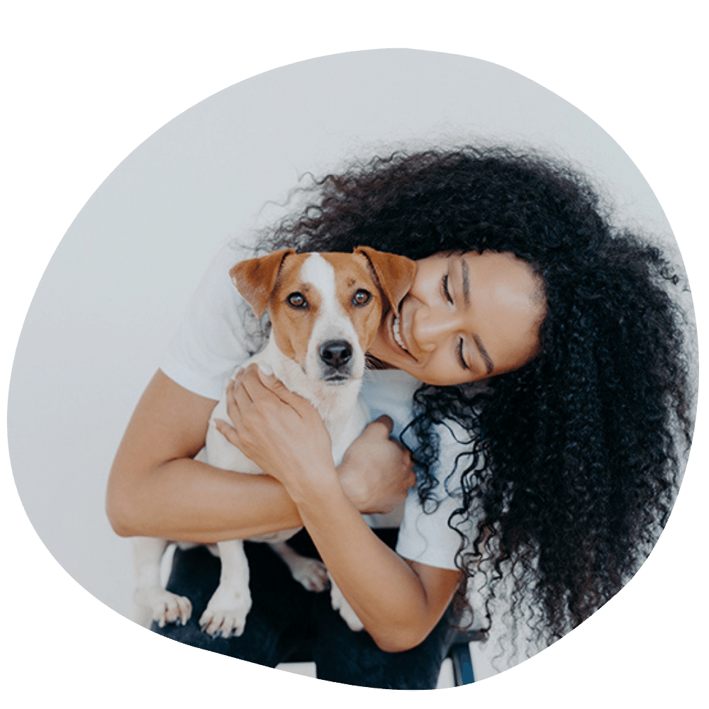 Curly haired dog mom hugging dog with brown patches around eyes after dog sitter services in Dubai