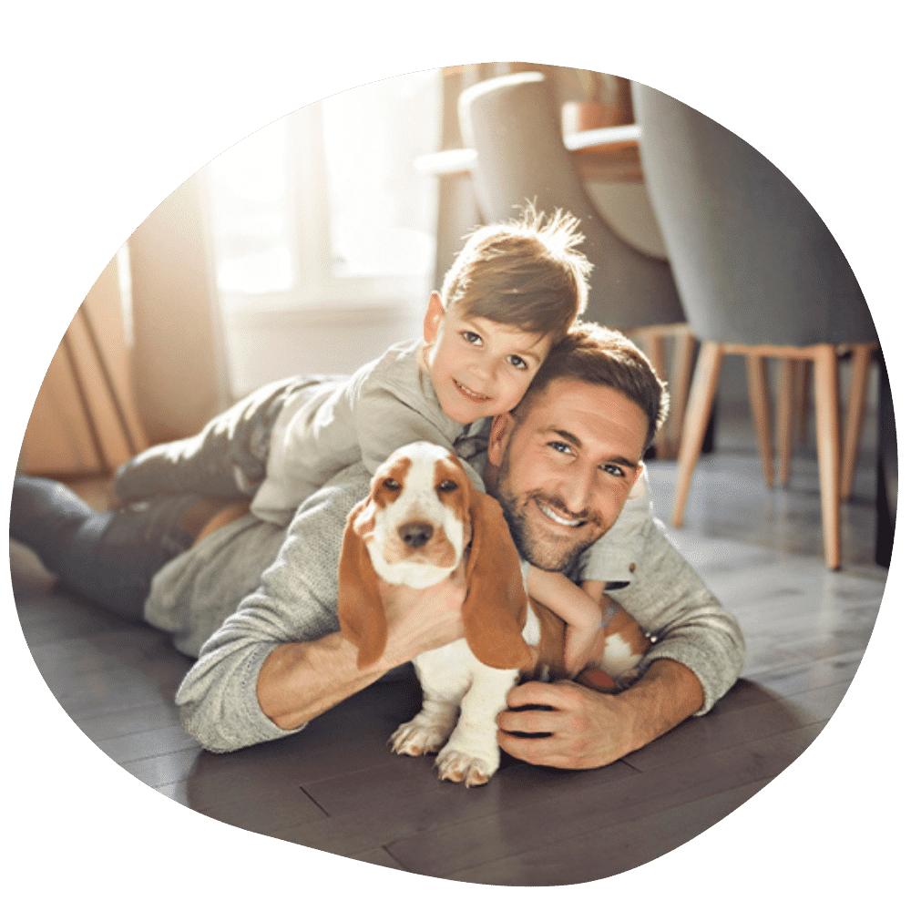 Father and son on ground wearing grey shirts hugging family dog after dog sitter services in Dubai