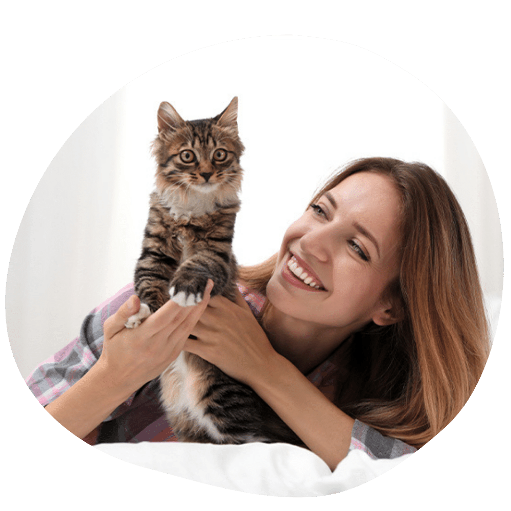 Female cat parent smiling on bed with cat in hand after best cat sitter service