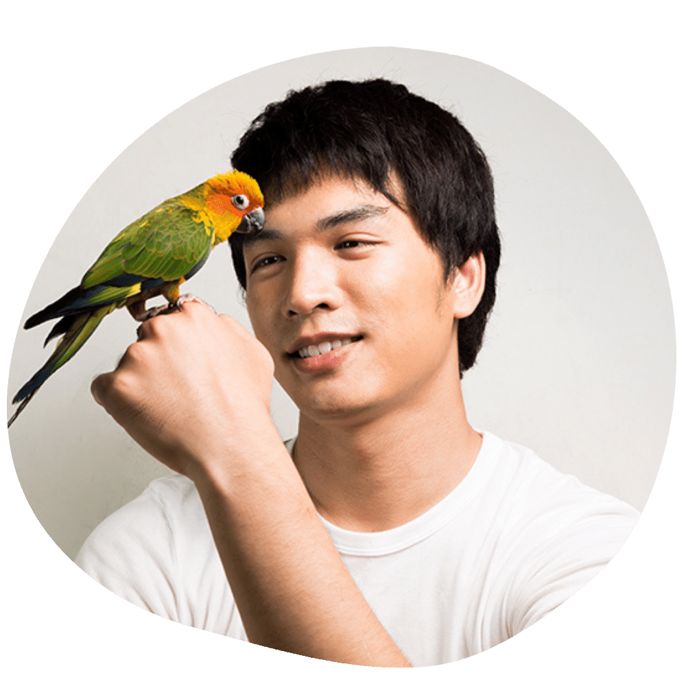 Happy conure parent wearing white shirt with conure on hand after bird sitting and in-home bird boarding services