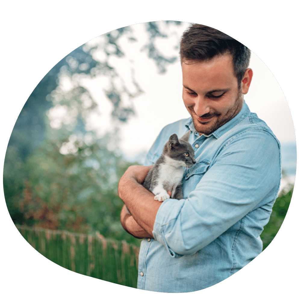 Male cat parent standing outside holding kitten in his arms after best cat sitter service