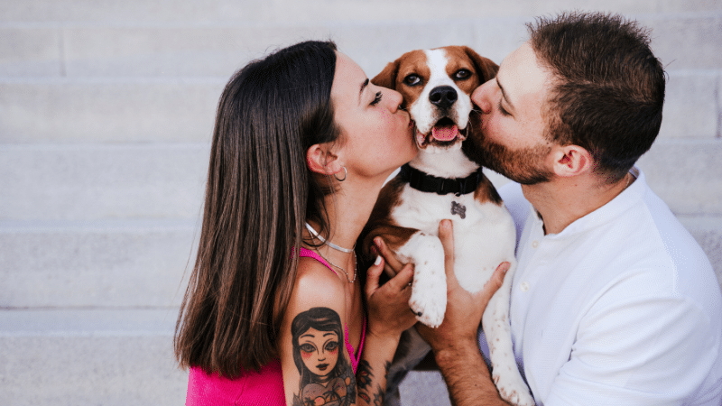 In-home dog sitters lovingly kissing their happy dog during pet care at home