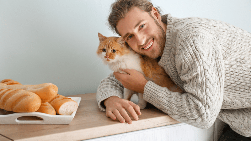 Trusted cat sitter smiling as the happy cat sits on table beside them