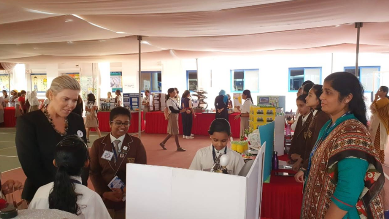 Foreign visitors analyzing a program at an Indian school with teachers and students during a school event in Sharjah.