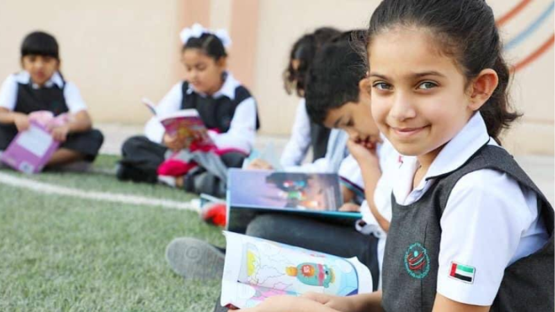 Four young students sitting together in a classroom studying and reading books at one of the best schools in Sharjah.