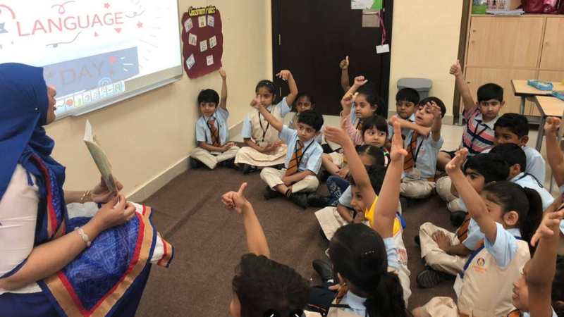 Teacher teaching English to many students sitting on the floor in a classroom at one of the best schools in Sharjah.