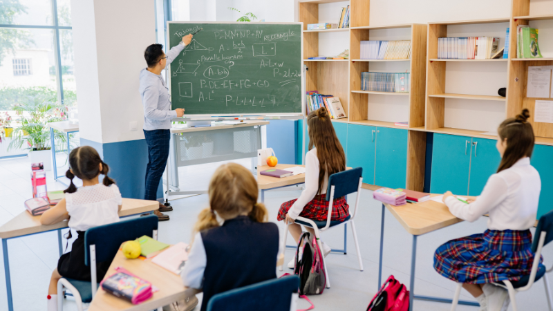 Students learning in a classroom with a teacher writing on the board at one of the best schools in Sharjah