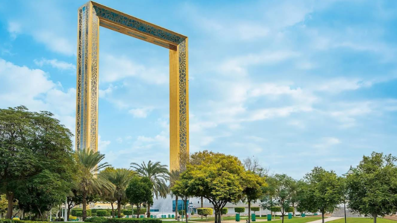 The iconic Dubai Frame standing inside Zabeel Park, surrounded by greenery with visitors walking and enjoying the scenic view
