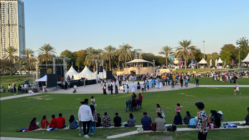 Large crowd walking and gathering at a concert in Zabeel Park, Dubai, enjoying live music in an open outdoor setting