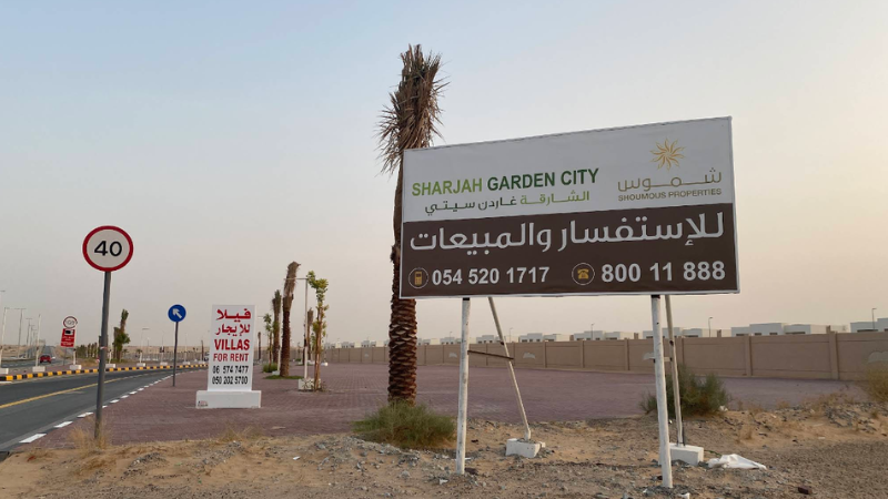 Banner displaying contact information beside a road with nearby buildings in an urban setting