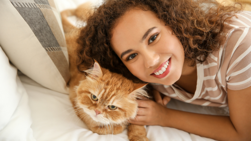 Woman relaxing beside her pet cat on a cozy bed