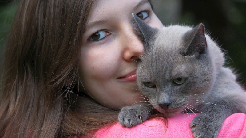 Cat owner holding a cat on their shoulder