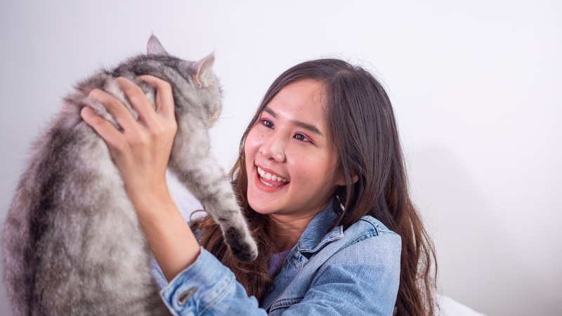 Woman holding her pet cat in her arms, enjoying a loving moment at home.