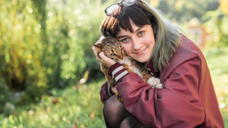 Female cat owner hugging her pet cat outdoors