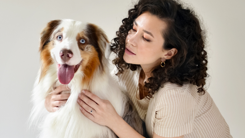 Female dog owner holding her pet dog indoors.