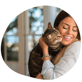 Brunette female cat parent wearing white shirt hugging cat after best cat sitter service
